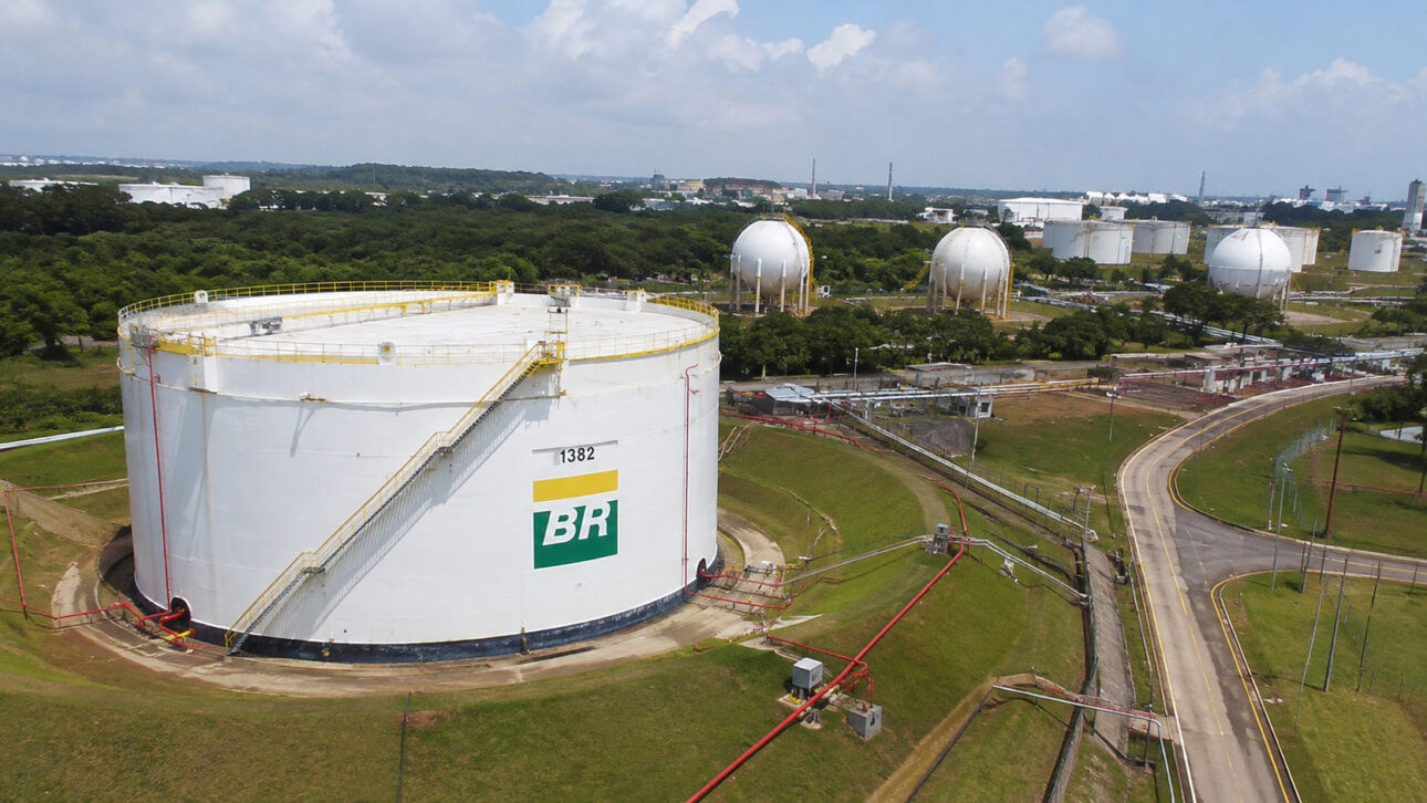 Instalação industrial com grandes tanques de armazenamento, tubulações e vias internas, ilustrando operações relacionadas à Transpetro e ao setor de petróleo e combustíveis.