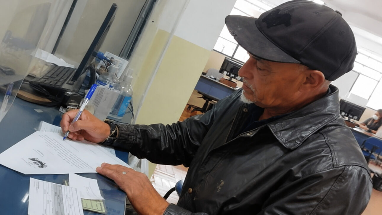 Homem de 60 anos preenche documento em ambiente de atendimento após participar da preparação para o concurso público de Taubaté.